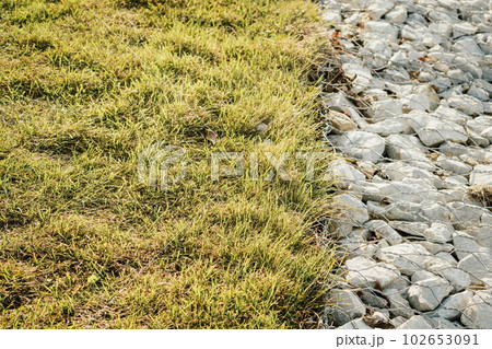 Granite stones behind a metal grate for strengthening the slope. Stones behind the wire. grey texture. construction. Granite stones behind a metal grate for strengthening the slope. Stones behind the wire. grey texture. construction. 102653091