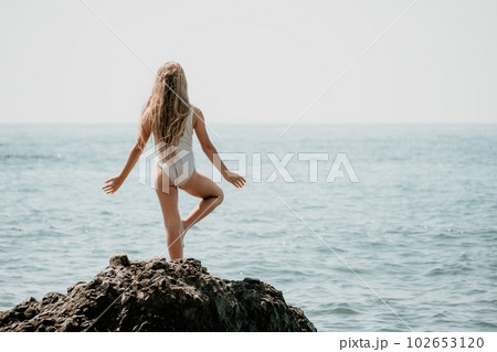Woman and her daughter practicing balancing yoga pose on one leg up together on rock in the sea. Silhouette mother and daughter doing yoga at beach 102653120