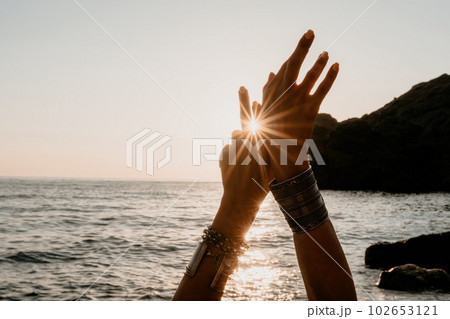 Woman sea yoga. Happy woman in white swimsuit and boho style braclets practicing outdoors on yoga mat by sea on sunset. Women yoga fitness routine. Healthy lifestyle, harmony and meditation Woman sea yoga. Happy woman in white swimsuit and boho style braclets practicing outdoors on yoga mat by sea on sunset. Women yoga fitness routine. Healthy lifestyle, harmony and meditation 102653121