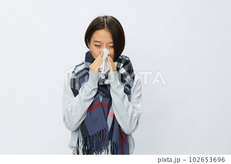 Asian woman cold flu holding a handkerchief stuffed nose with fever sick from the virus on a white background, copy place Asian woman cold flu holding a handkerchief stuffed nose with fever sick from the virus on a white background, copy place 102653696
