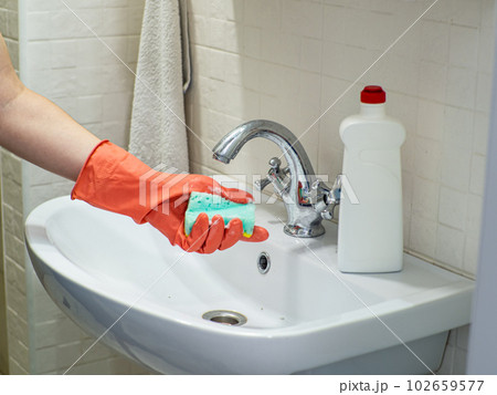Person hand holding a mint sponge and washing it under water Person hand holding a mint sponge and washing it under water 102659577
