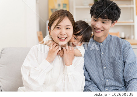 リビングのソファーでくつろぐ若い家族 102660339