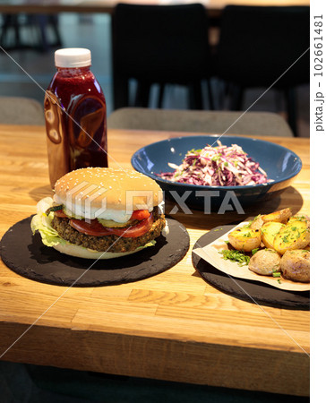 Lunch on the counter in the shopping center, business center. Burger, fries, cole salad and drink. 102661481