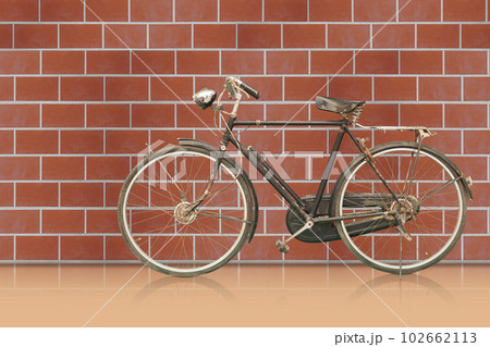 side view antique and rust black frame bicycle on orange floor, brown brick wall background, object, decor, transport, copy space 102662113