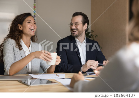 Laughing colleagues engaged in briefing gathered in conference room Laughing colleagues engaged in briefing gathered in conference room 102664137