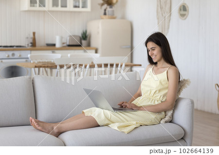 Cheerful positive relaxed girl resting on sofa with laptop Cheerful positive relaxed girl resting on sofa with laptop 102664139