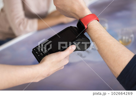 Closeup guy paying bill, apply smartwatch on POS terminal machine 102664269