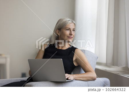 Thoughtful positive blonde mature woman resting in armchair Thoughtful positive blonde mature woman resting in armchair 102664322