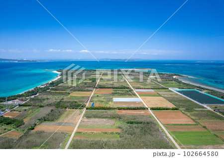 【沖縄・津堅島・空撮写真】津堅島と周辺に広がる青い海、直線の道を空撮 102664580