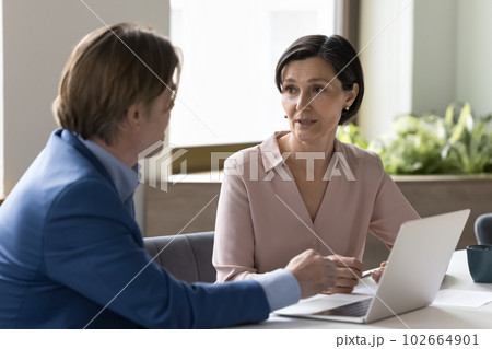 Two business people talking sit at desk with laptop 102664901