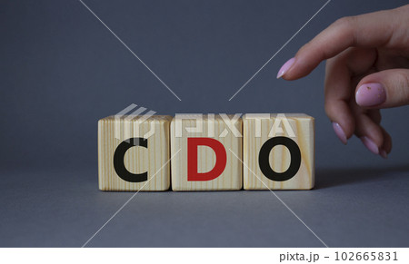 CDO - Collateralized Debt Obligation symbol. Wooden cubes with word CDO. Beautiful grey background. Businessman hand. Business and Collateralized Debt Obligation concept. Copy space. 102665831