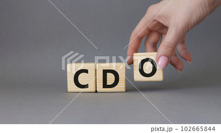 CDO - Collateralized Debt Obligation symbol. Wooden cubes with word CDO. Beautiful grey background. Businessman hand. Business and Collateralized Debt Obligation concept. Copy space. 102665844