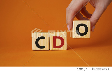 CDO - Collateralized Debt Obligation symbol. Wooden cubes with word CDO. Beautiful orange background. Businessman hand. Business and Collateralized Debt Obligation concept. Copy space. 102665854
