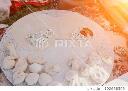 woman's hands making qutab or chebureki with a rolling pin and minced meat onion in dough for culinary concepts related to Azerbaijani, Tatar and Greek cuisine, as well as empanadas in Latin America. woman's hands making qutab or chebureki with a rolling pin and minced meat onion in dough for culinary concepts related to Azerbaijani, Tatar and Greek cuisine, as well as empanadas in Latin America. 102666506
