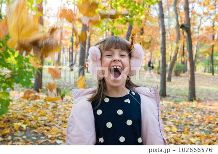 Outdoor portrait of happy little girl in autumn park with falling leaves 102666576
