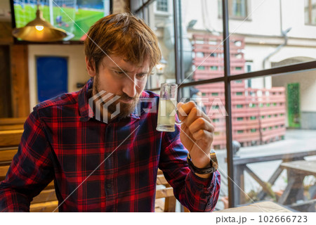 A man sits alone at a table in a bar and drinks strong alcohol. Alcoholism, alcohol addiction 102666723