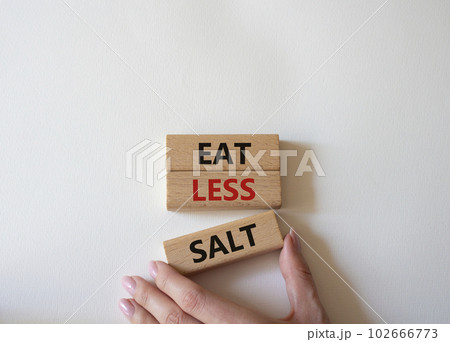 Eat less salt symbol. Concept word Eat less salt on wooden blocks. Businessman hand. Beautiful white background. Business and Eat less salt concept. Copy space 102666773