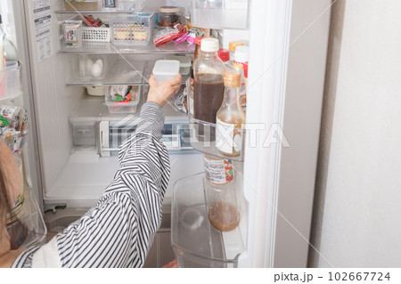 【冷蔵室からタッパを取り出す主婦】 102667724