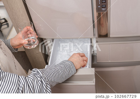 【製氷室から氷をグラスに入れる主婦】 102667729