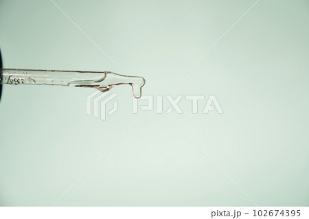 Natural medicine, cosmetic research. The concept of skin care and its analysis. Dermatology. With space to copy. Laboratory pipette with a drop of serum, oil, cosmetics. High quality photo 102674395