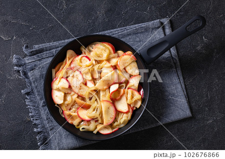 fried onion and red apple slices on skillet 102676866