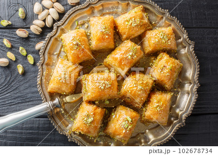 Turkish traditional delight baklava with pistachio on a wood background closeup. Horizontal top view Turkish traditional delight baklava with pistachio on a wood background closeup. Horizontal top view 102678734