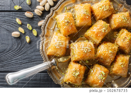 Traditional Turkish dessert pistachio baklava with honey close-up in a plate. Horizontal top view 102678735