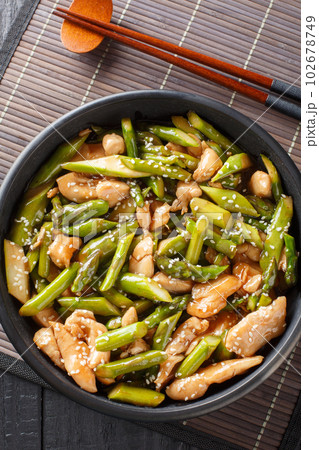 stir fry chicken with asparagus in spicy sauce close-up in a bowl. Vertical top view 102678749