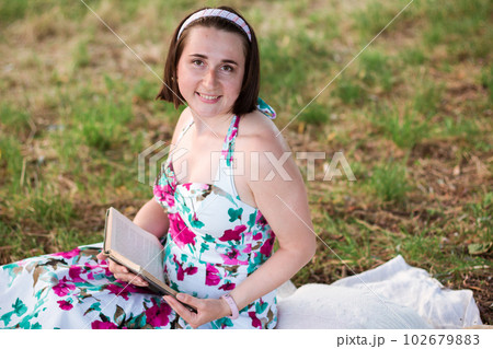 A young woman sitting on a picnic in a park A young woman sitting on a picnic in a park 102679883