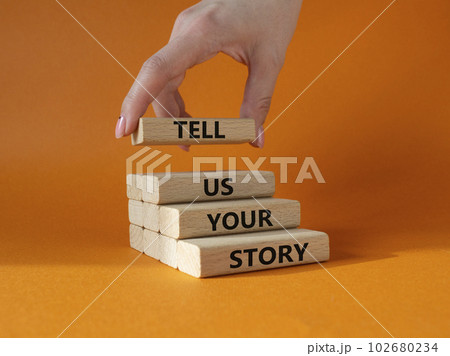 Tell us your story symbol. Concept words Tell us your story on wooden blocks. Beautiful orange background. Businessman hand. Business and Tell us your story concept. Copy space. Tell us your story symbol. Concept words Tell us your story on wooden blocks. Beautiful orange background. Businessman hand. Business and Tell us your story concept. Copy space. 102680234