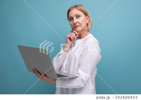 portrait of successful mature business woman with blond hair surfing the internet using laptop portrait of successful mature business woman with blond hair surfing the internet using laptop 102680433