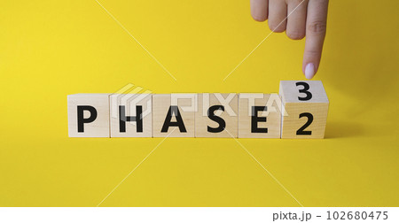 From Phase 2 to 3 symbol. Businessman Hand points at wooden cubes with words Phase 2 and Phase 3. Beautiful yellow background. Business and Phase concept. Copy space From Phase 2 to 3 symbol. Businessman Hand points at wooden cubes with words Phase 2 and Phase 3. Beautiful yellow background. Business and Phase concept. Copy space 102680475