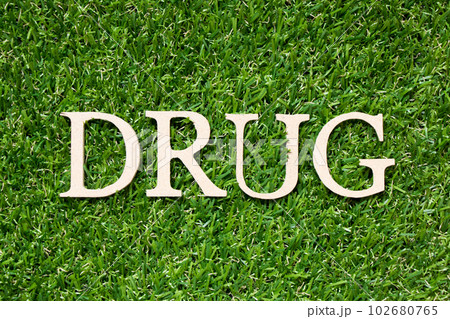 Wood alphabet letter in word drug on artificial green grass background Wood alphabet letter in word drug on artificial green grass background 102680765
