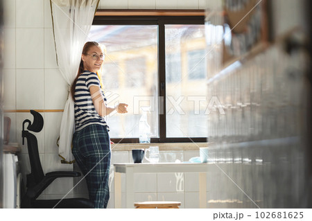 A woman housewife in stripped t-shirt washing a window at the kitchen - looking in the camera A woman housewife in stripped t-shirt washing a window at the kitchen - looking in the camera 102681625