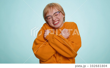 Young happy blonde woman in glasses spread hands and give hug embrace to you on blue background 102681804