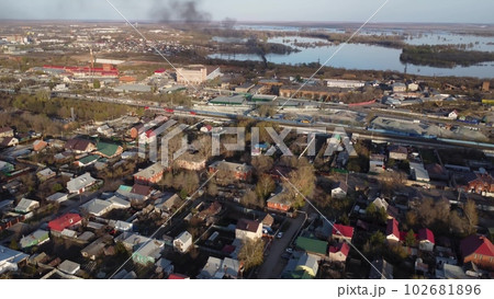 Cottage houses top view from a drone. Flight over the city. There is black smoke near the river. Cottage houses top view from a drone. Flight over the city. There is black smoke near the river. 102681896