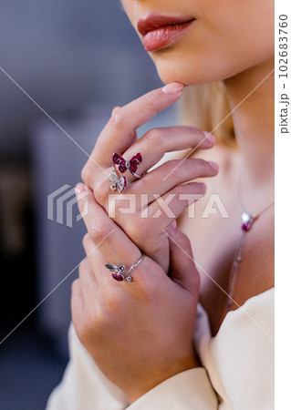 Girl's hand displays a precious and exquisite diamond and gold ring. A woman in a jewelry store. The focus is on the close-up shot of hands adorned with rings. Girl's hand displays a precious and exquisite diamond and gold ring. A woman in a jewelry store. The focus is on the close-up shot of hands adorned with rings. 102683760