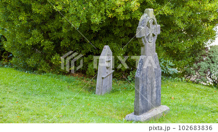 An ancient stone tombstone in the form of a Celtic cross near Saint Fin Barre's Cathedral in Ireland. Old stone crosses at a cemetery. Religious objects. 102683836