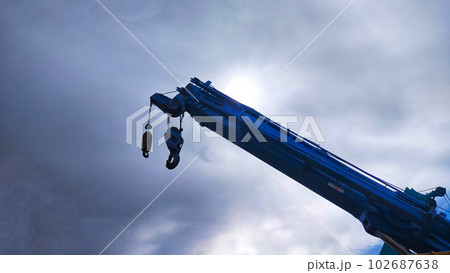 Blue telescopic crane soaring into the sky with blue sky background. Blue telescopic crane soaring into the sky with blue sky background. 102687638