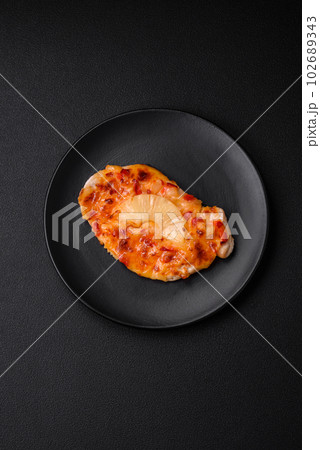 Grilled chicken fillet in the form of a steak with tomatoes, pineapple and cheese 102689343