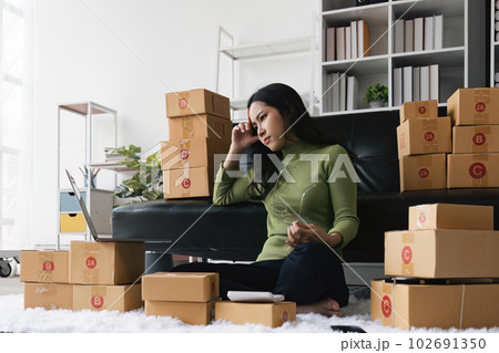 Young startup small business entrepreneur woman packing package post shipping box preparing delivery parcel , Online business, ecommerce and delivery concept. stressed headache 102691350
