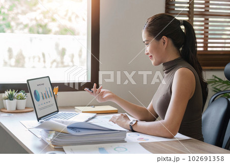 Asian businesswoman sit at their desks at home and calculate financial graphs showing results about their investments, plan a successful business growth process 102691358
