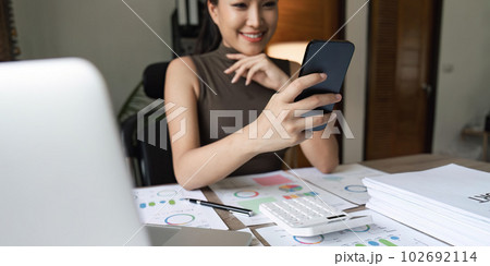 Asian businesswoman in home happy and cheerful during using smartphone and working 102692114