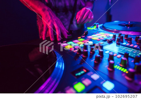 Close up of DJ hands on dj console mixer during concert in the club 102695207