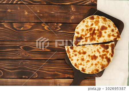 Baked homemade flatbread on wooden background close up Baked homemade flatbread on wooden background close up 102695387