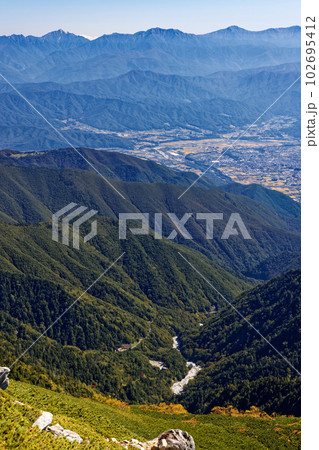 秋の中央アルプス・主稜線縦走路から見る南アルプスと伊那谷の町並み 102695412