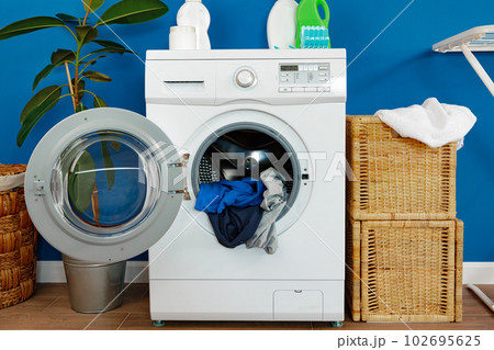 Washing machine with laundry on blue wall background 102695625