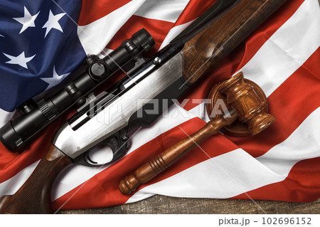 Wooden judge gavel and hunting rifle over USA flag on wooden background Wooden judge gavel and hunting rifle over USA flag on wooden background 102696152