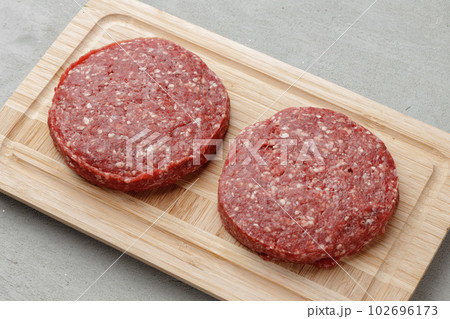 Raw beef burger patty on wooden board 102696173