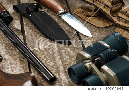 Hunting equipment on old wooden background including rifle, knife, binoculars and cartridges Hunting equipment on old wooden background including rifle, knife, binoculars and cartridges 102696434